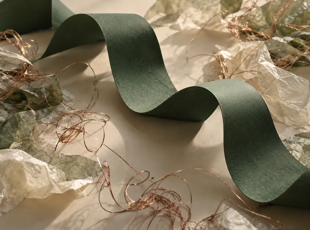 A physical green paper sculpture with copper filaments suggesting speech amid noise